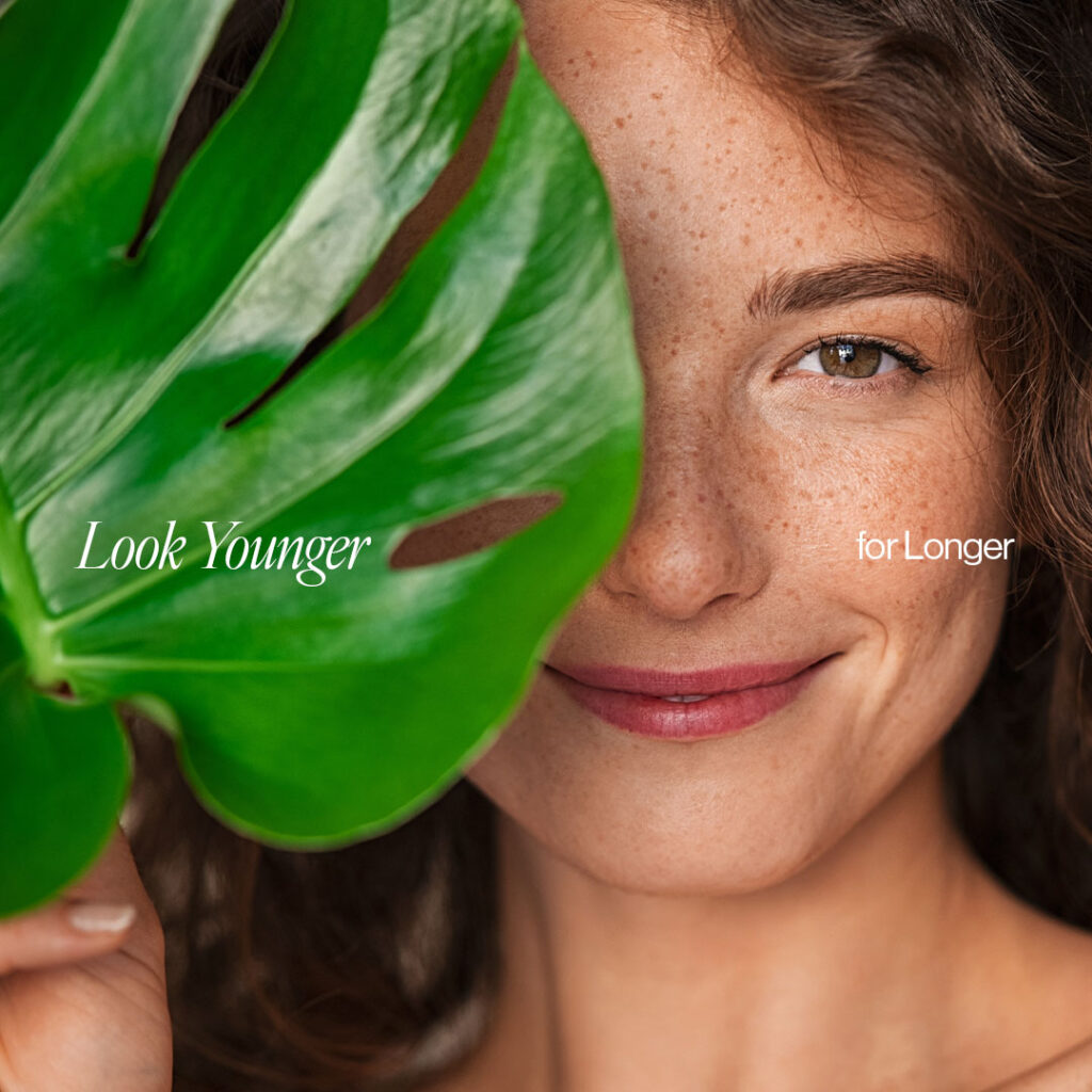 smiling woman with freckles holding up a big leaf with the words Look Younger for Longer