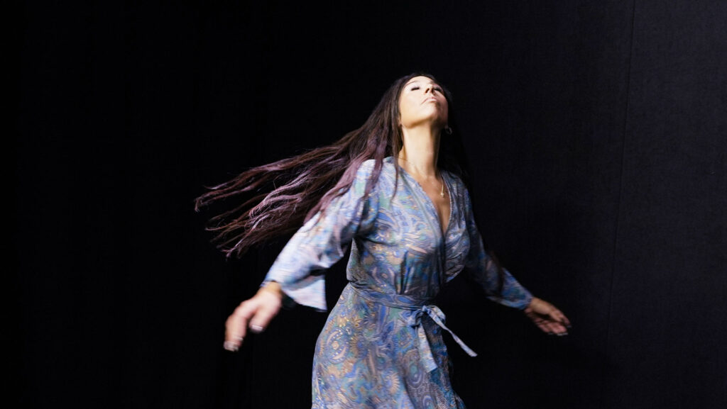 quantum healing practitioner Audrey Love dances in a spacious black studio