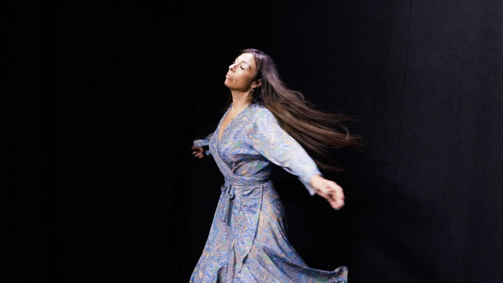 quantum healing practitioner Audrey Love dances in a spacious black studio